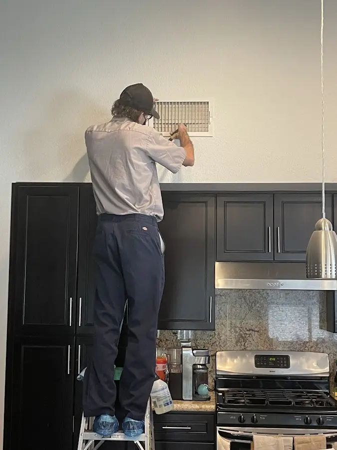 Technician inspecting an air vent during HVAC service in Merrimac